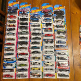 Diecast car lot with multiple Hot Wheels cars in blister packages, assorted colors