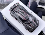 Diecast racing model toy car with dark body and pink trim, front-top view