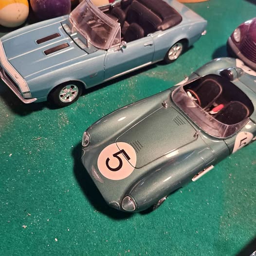 Diecast toy cars, light blue roadsters with open tops, one marked with number 5