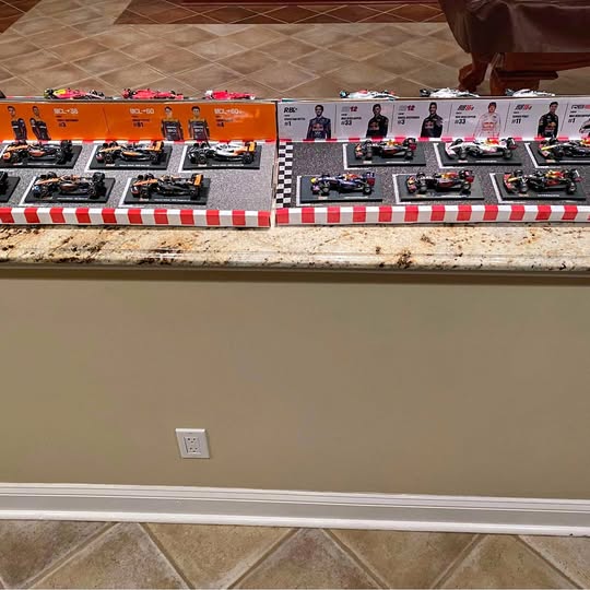 Diecast vehicle display set with multiple race cars in orange and white boxes