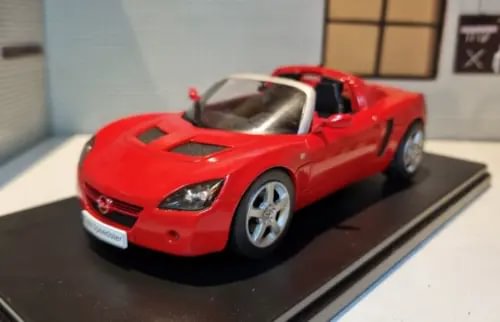 Red diecast model car with black hood stripes, front three-quarter view (1:24 scale)