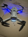 White quadcopter drone with four black propellers and blue LED lights