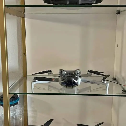 Compact quadcopter drone with four propellers resting on a white platform