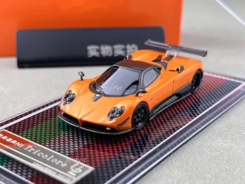 Orange racing sports diecast model car with black wheels and rear wing on base