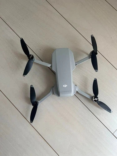 Folding DJI drone with four propellers and controller-like body, gray