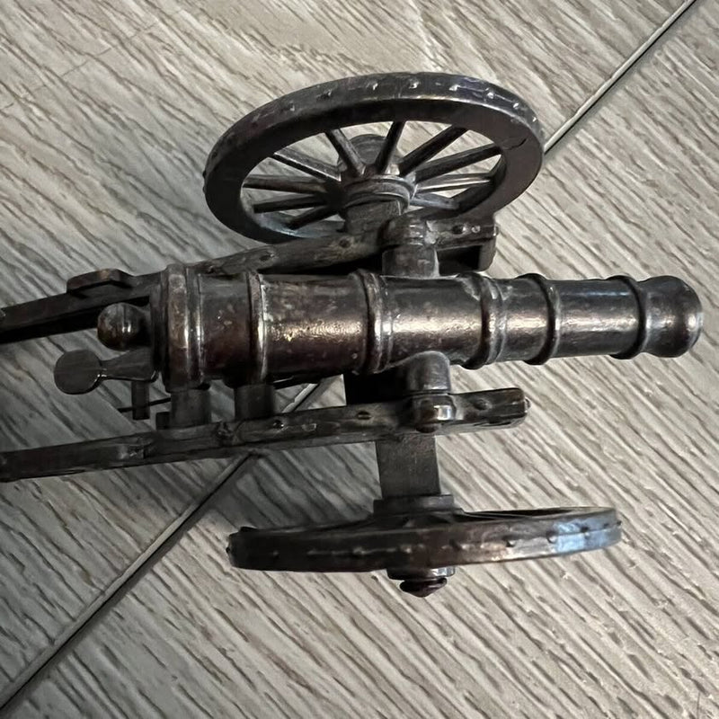 Vintage diecast spring-action artillery cannon with metal barrel and wheel mount