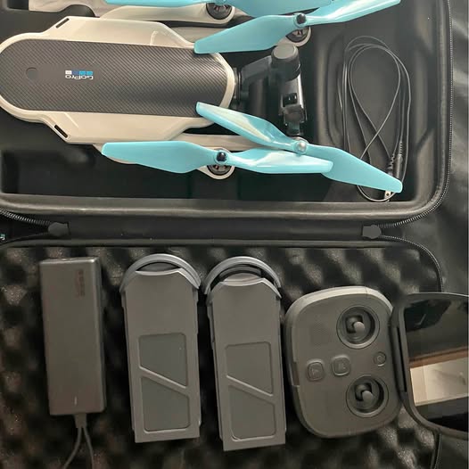 Folding drone in hard travel case with teal propellers and controller modules