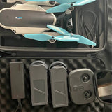 Folding drone in hard travel case with teal propellers and controller modules