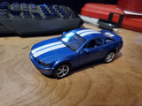 Blue diecast sports car with white racing stripes, front three-quarter view