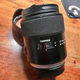 Black Tamron camera lens barrel with focus markings and hood mount