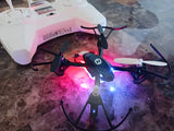 Quadcopter drone with LED lights and four propellers, gray body.
