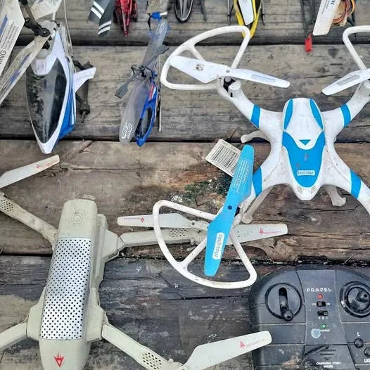 Assorted white quadcopter drone parts with propellers, on a surface
