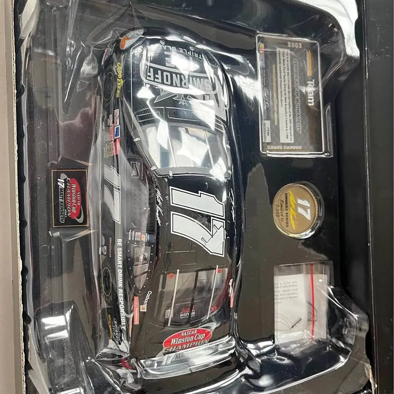 1:24 NASCAR diecast race car in clear packaging, black with white racing graphics.