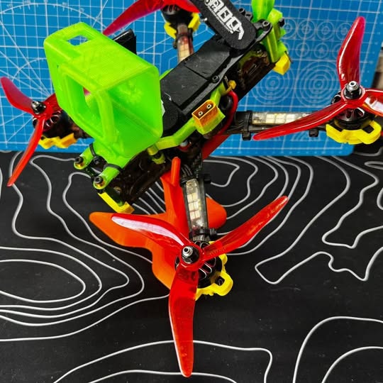FPV racing drone with neon green canopy and red orange propellers