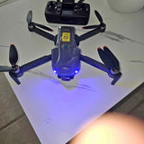 Quadcopter drone with blue LED on body and four propellers