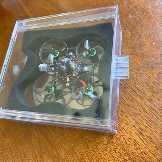 FPV whoop drone in clear protective case with green propellers