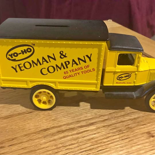 Yellow diecast delivery truck with black cab and side panel text