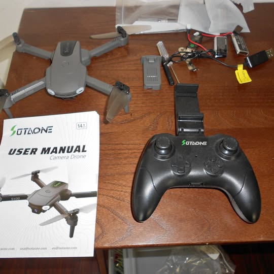 Drone controller with user manual, drone parts and battery packs on a table