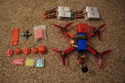 Red FPV freestyle drone with propellers, battery, and wiring accessories