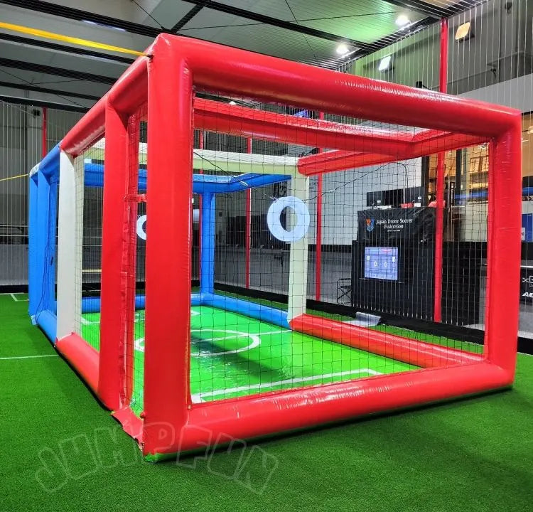 Red inflatable drone training cage with black mesh net walls and padded frame.