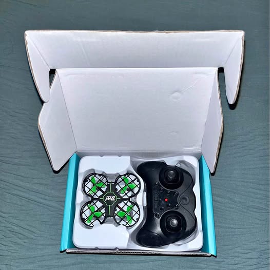 Children toy drone set with green prop guards and black controller, in open box