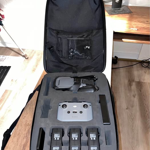 Open black drone carrying case with folded drone and multiple batteries