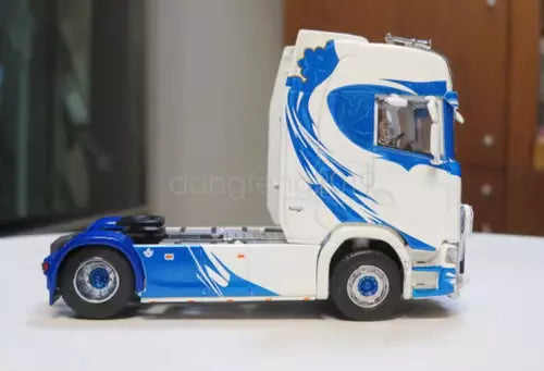 Blue and white diecast tractor unit truck, side view with detailed grille and wheels