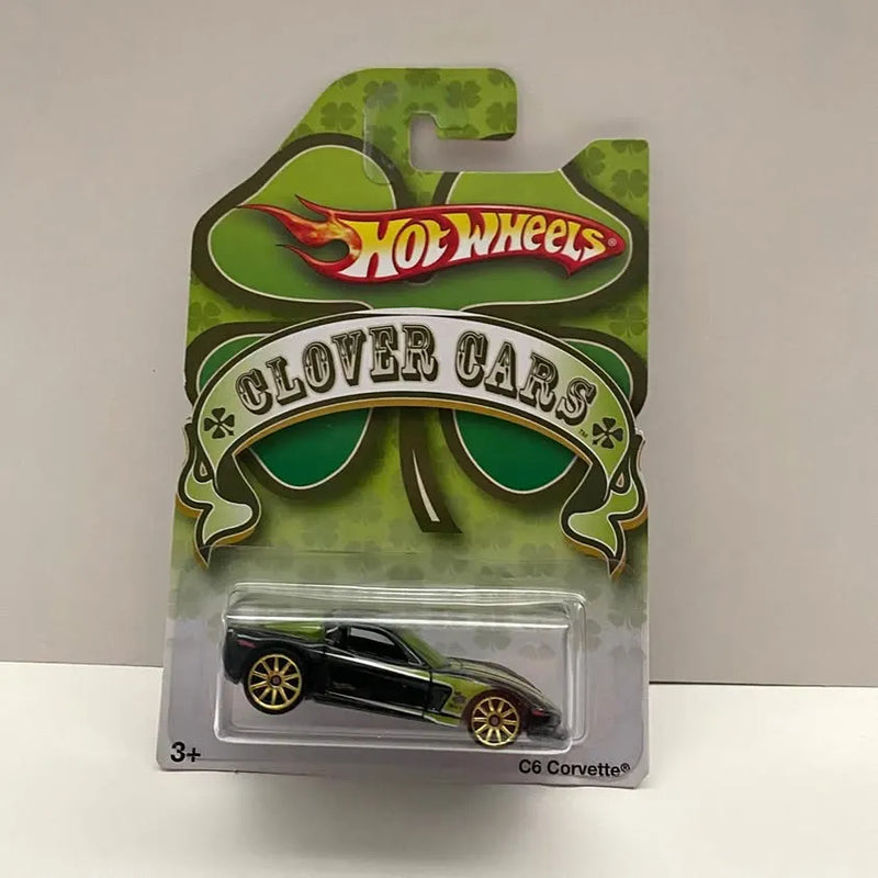 Diecast car blister pack, black body, gold wheels, green clover Hot Wheels graphics