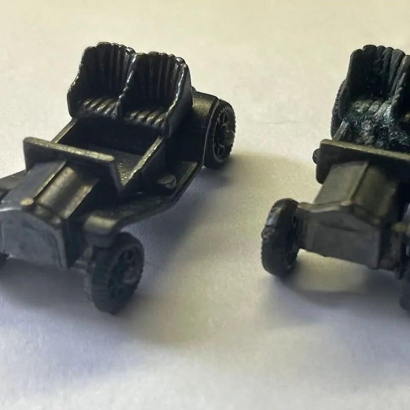 Vintage diecast toy vehicle pair with olive-gray body and black seats, open top