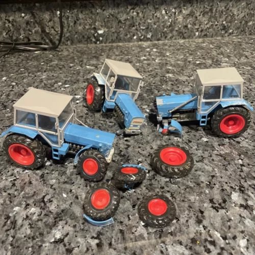 Set of blue diecast tractor models with beige cabs and red wheels, plus parts