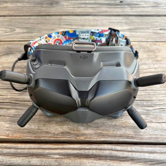 Gray quadcopter drone with front sensors, side prop arms, and landing skids