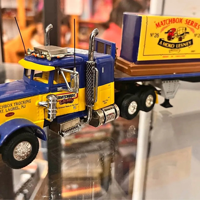 Blue and yellow diecast metal tractor trailer model with trailer hitch