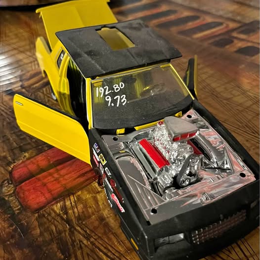 Yellow diecast car with open hood, chrome engine detail visible
