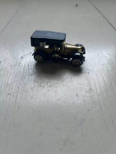 Vintage diecast automobile model, dark body with gold trim and black wheels