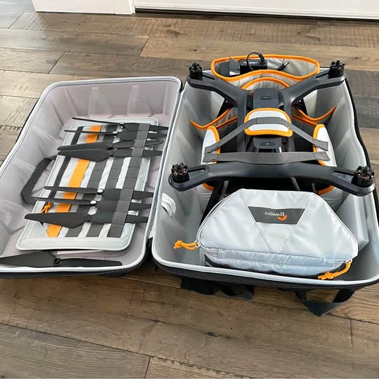 Folding drone case with black drone and orange accents, controller pouch inside