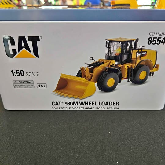 Yellow diecast wheel loader model with front bucket, CAT branding on packaging