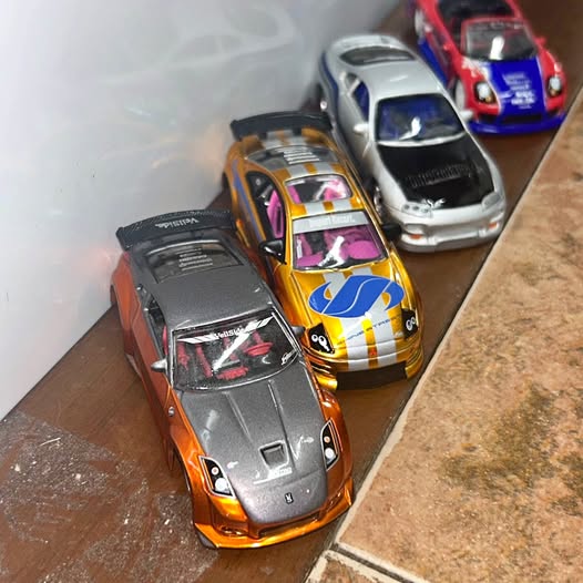 Diecast race car toy, orange with black hood and racing decals, front angled view