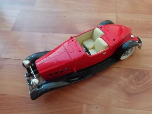 Red die-cast speedster coupe model car with black fenders and open cockpit
