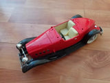 Red die-cast speedster coupe model car with black fenders and open cockpit