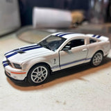 Diecast sports car model, white with blue racing stripes, front 3/4 view