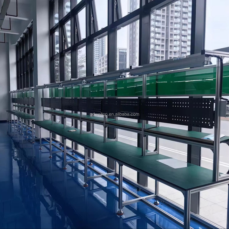 Metal-framed assembly workbench conveyor with green shelves and tabletop rails