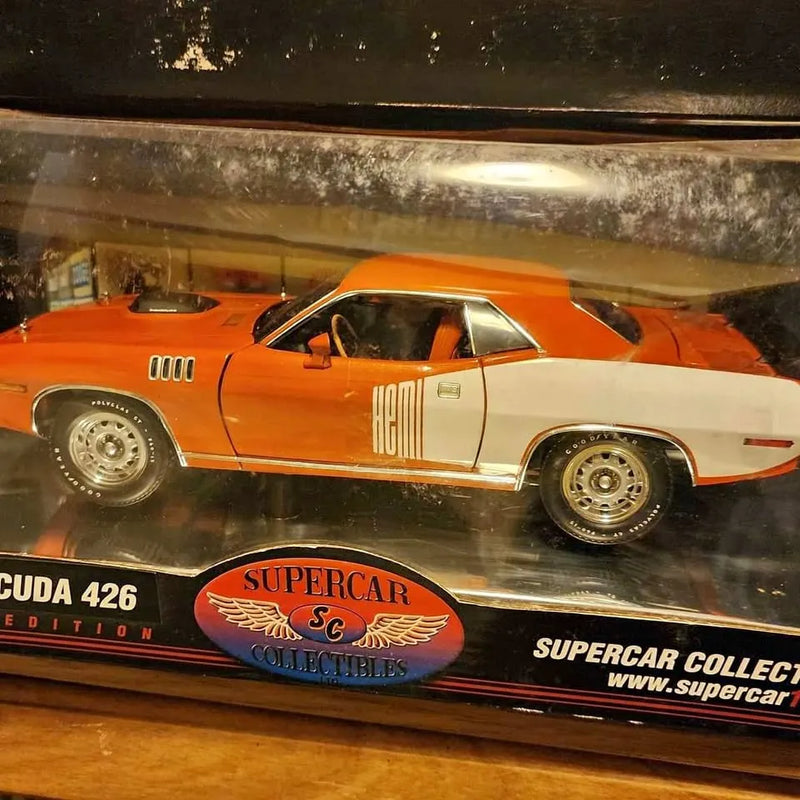 Orange and white diecast sports car model with rear spoiler, in display case