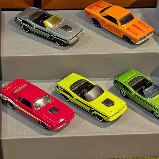 Diecast muscle car display with red, green, yellow, gray, orange cars in tray