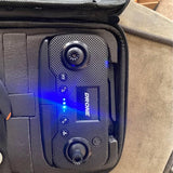 Mini drone with dark gray body, blue indicator lights, and front camera lens