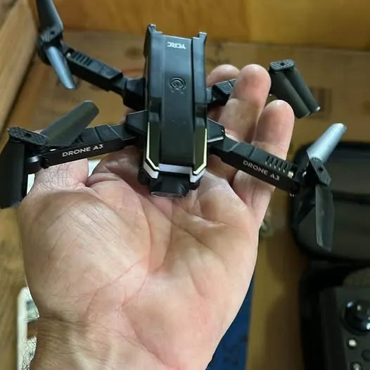 Small foldable drone with four propellers and front camera module, dark gray.