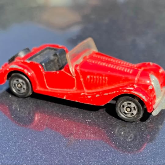 Red diecast sports car, open cockpit, black wheels, detailed bodywork