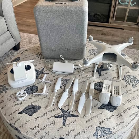 White drone with propellers, controller, batteries, and gray storage case