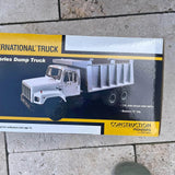 Diecast dump truck toy in retail box with gray and white truck and raised bed
