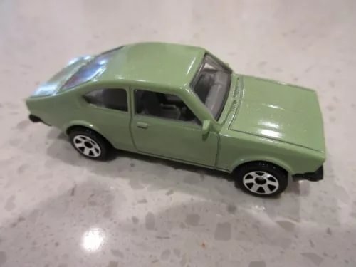 Light green diecast toy coupe race car, side view with black wheels