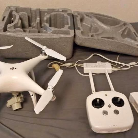 White quadcopter drone with remote controller and batteries in gray case